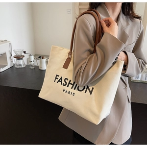 Chic cream canvas tote bag with brown leather straps shown in a stylish cafe setting
