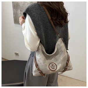 Detail of washed grey canvas crossbody bag with brown leather strap and silver M logo
