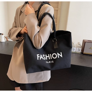 Detail of black canvas tote bag with FASHION PARIS print and glossy leather straps