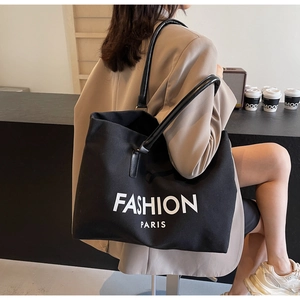 Detail of black canvas tote bag featuring Fashion Paris print and leather handles