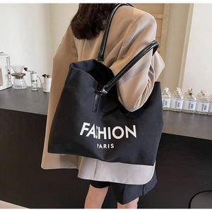Detail of black canvas tote bag with Fashion Paris print and leather shoulder straps
