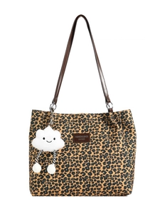 Fashionable leopard print tote bag with brown leather straps and plush charm on white background