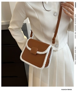 Detail showing the brown leather crossbody bag with white faux fur trim on a model