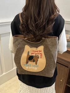 Brown vintage canvas tote bag with cat embroidery shown on a model in a warm interior