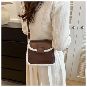 Detailed close-up of brown leather square bag with white faux fur trim and metal buckle