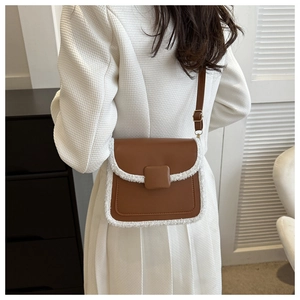 Detailed view of the brown leather crossbody bag with white faux shearling fur trim