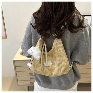 Model wearing yellow tote bag with white jacquard pattern and plush cloud charm