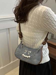 Sac bandoulière en denim gris avec nœud argenté et perles porté par un mannequin