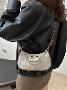 Sac sous le bras chic avec nœud et chaînes de perles dans un style urbain élégant