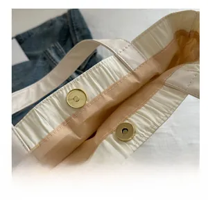 Detail shot of the magnetic snap closure on the pleated cream nylon bucket bag with satin lining