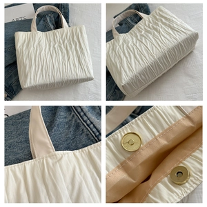 Detail view of ivory pleated nylon tote bag with magnetic gold closure and inner lining