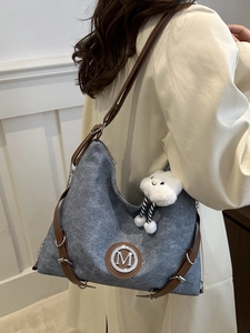 Gray textured fabric crossbody bag with brown leather strap and plush cloud charm