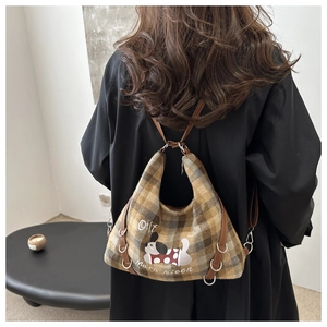 Close-up of retro plaid tote bag with cartoon dog embroidery and leather strap detail