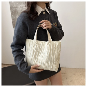 Detailed view of the off-white pleated tote bag showing its soft vertical texture and handle