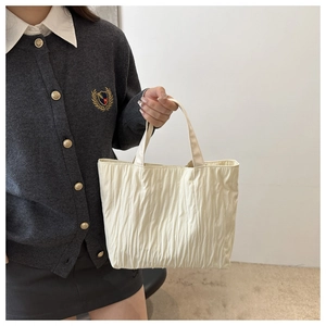 Detailed close-up of cream-white pleated tote bag showing fabric texture and soft pleats