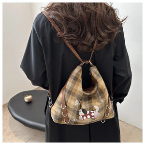 Detail of vintage plaid tote bag with cartoon dog print and brown leather straps
