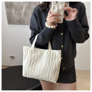 Detail of white pleated tote bag showing the vertical texture and soft leather material
