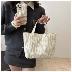 Detail of soft pleated texture on cream-colored large tote bag with shoulder handle
