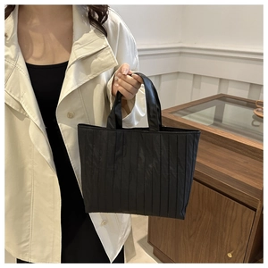 Detail of black pleated tote bag showing fine vertical pleats and silky fabric texture