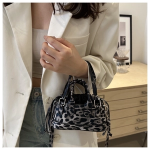 Close-up of leopard print mini handbag with black handles and detachable shoulder strap
