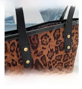 Dettaglio della borsa leopardata con rivetti in metallo dorato e manico in pelle nera