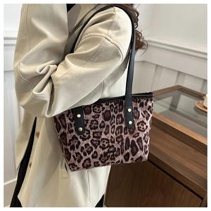 Dettaglio della borsa tote leopardata con manici neri e borchie dorate sul cappotto beige