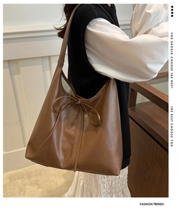 Detailed view of brown leather shoulder bag with a stylish bow knot and spacious interior