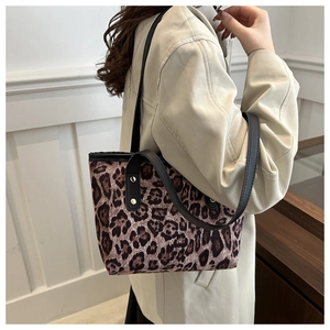 Dettaglio della borsa tote leopardata con spallacci in pelle nera e rivetti d'argento