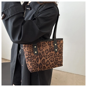 Dettaglio della borsa leopardata con manici in pelle nera e borchie dorate lucide