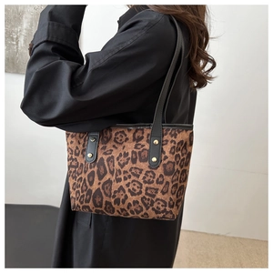 Dettaglio della borsa tote leopardata con cinturini in pelle nera e rivetti dorati