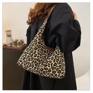 Detailed view of leopard print hobo bag with brown leather strap worn over the shoulder
