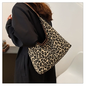 Close-up of leopard print canvas hobo bag with dark brown strap on a model's shoulder
