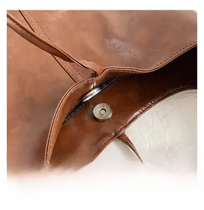 Close-up of the magnetic buckle closure on a vintage brown leather bucket bag