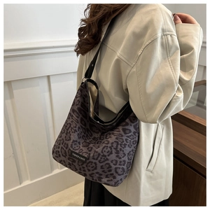 Détail d'un sac hobo à motif léopard avec bandoulière en cuir noir et tissu suédé