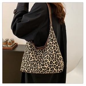 Detail of leopard print canvas tote bag with brown leather straps and crescent shape design