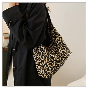 Close-up of leopard print canvas hobo bag worn with a black trench coat for daily styling