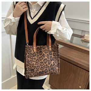 Detail view of leopard print tote bag with brown leather handles and metal rivets