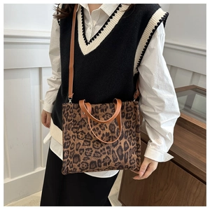 Detail of leopard print tote bag with brown leather handles and adjustable shoulder strap
