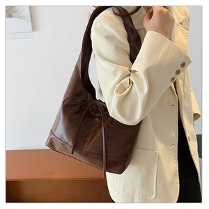 Detail shot of vintage dark brown hobo bag with lace-up bow and glossy leather texture