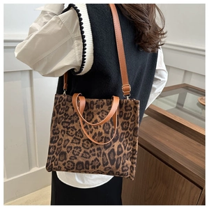 Detail of leopard print canvas tote bag with brown leather handles and premium texture