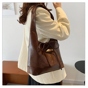 Detail of dark brown leather tote bag with stylish bow accent and minimalist vintage design