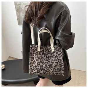 Detail shot of a leopard print tote bag styled with a leather jacket on model
