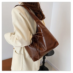Detail of a dark brown tote bag with a bow accent and vintage leather texture