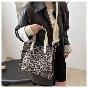 Detail of leopard print tote bag with contrast cream leather straps and adjustable shoulder belt