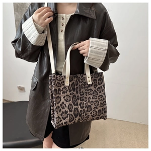 Detail of stylish leopard print tote bag with cream leather handles worn with leather jacket