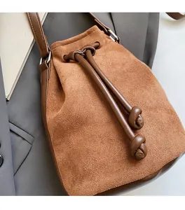 Dettaglio della borsa a secchiello vintage in pelle scamosciata marrone su blazer