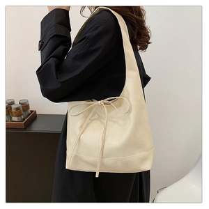 Side view of a large cream hobo tote bag featuring a decorative bow knot strap detail