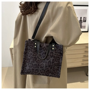 Detail of leopard print tote bag with black leather straps and gold stud accents