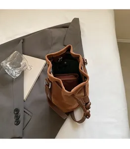 Dettaglio della borsa a secchiello in pelle scamosciata marrone con interno spazioso e clip