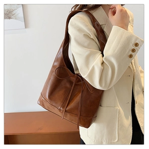 Detail view of a brown vintage tote bag with a decorative leather bow and polished finish